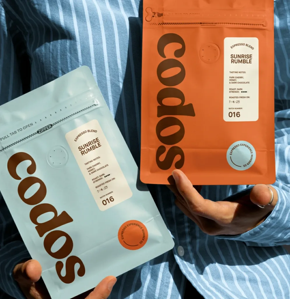 Two color matching flat bottom coffee pouches with air valve held in hands